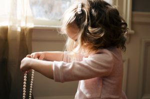 Little girl holding a pearl necklace