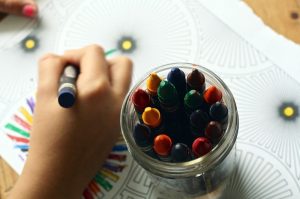 Child coloring with crayons on a table