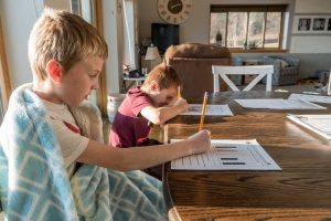 2 boys studying answering some worksheets on a table at home